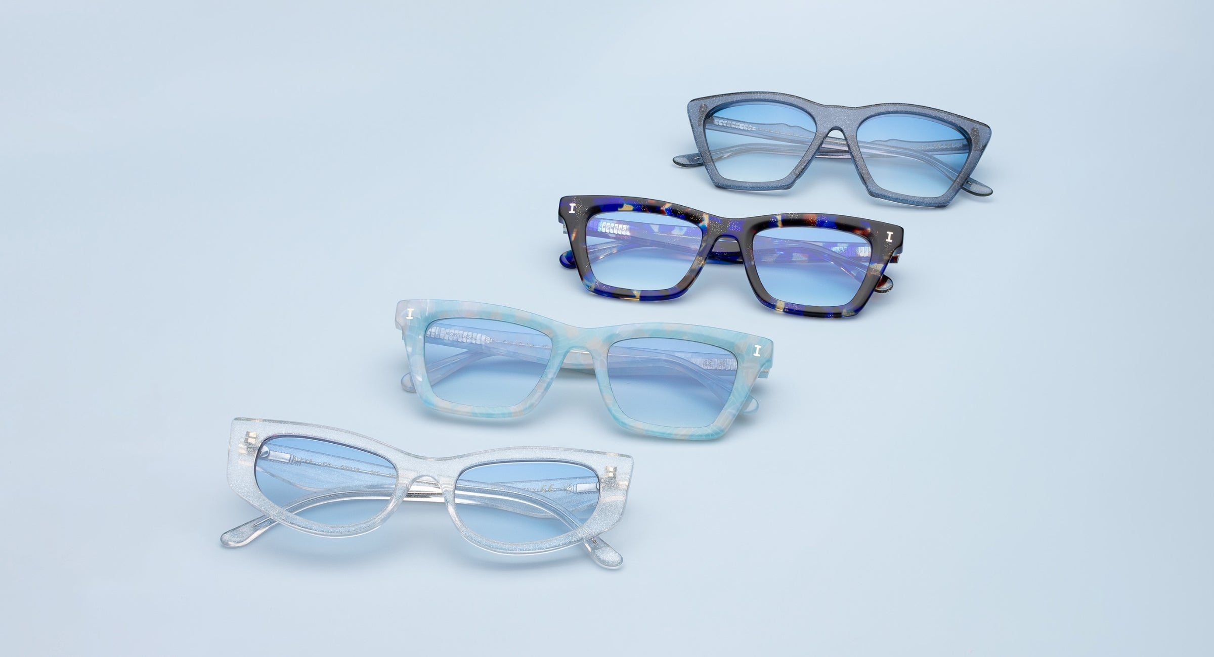 Lisbon, Portugal, and Alexa Sunglasses with blue see-through lenses displayed over an icy blue backdrop