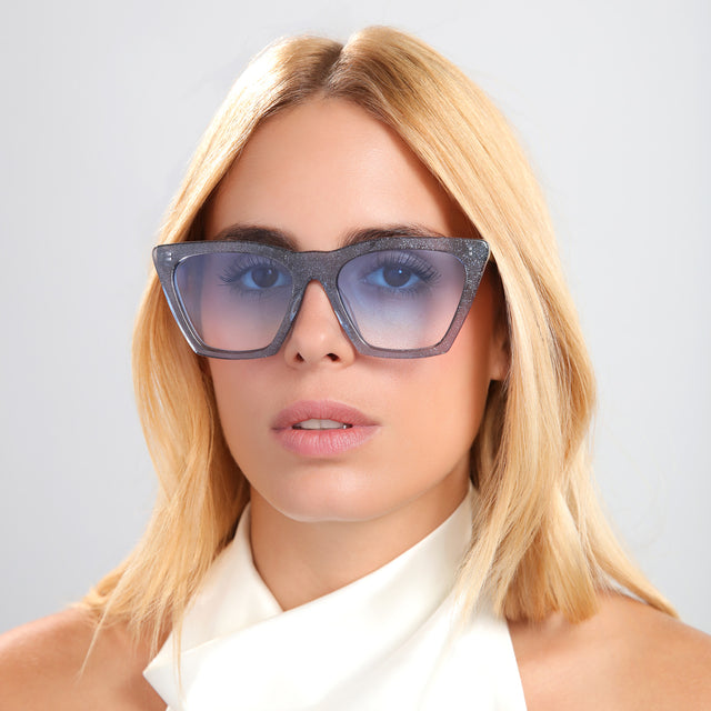 Blond woman in a white silk halter top wearing Lisbon Sunglasses Stardust with Blue Gradient See Through