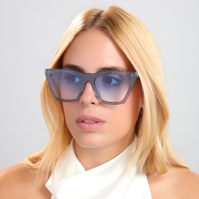 Another angle of blond woman in a white silk halter top wearing Lisbon Sunglasses Stardust with Blue Gradient See Through