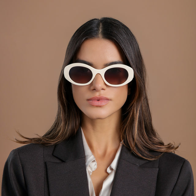 Brunette model in a black wool blazer wearing Luna Sunglasses Cream with Brown Flat Gradient