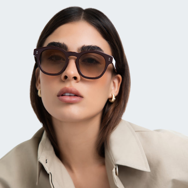 Woman in a trench coat wearing Madison Sunglasses Bordeaux with Taupe Gradient