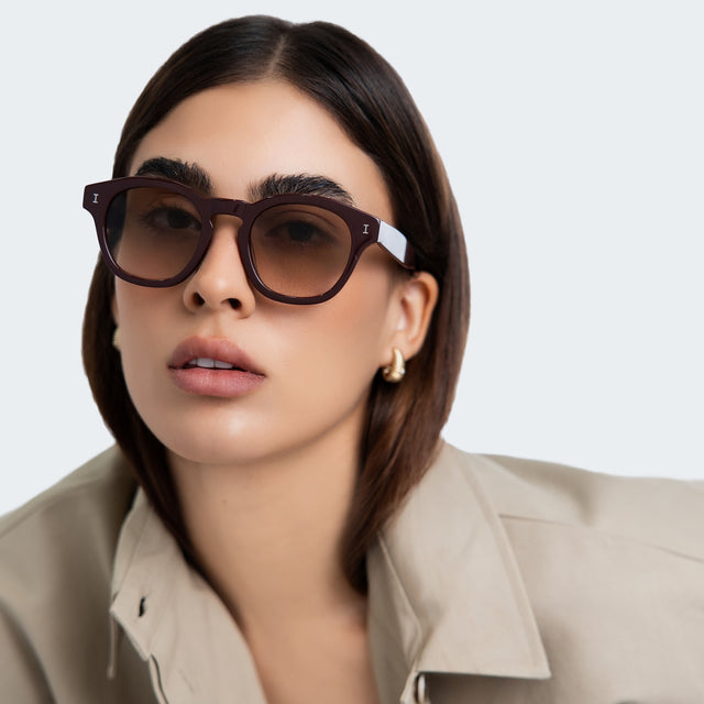 Another angle of woman in a trench coat wearing Madison Sunglasses Bordeaux with Taupe Gradient