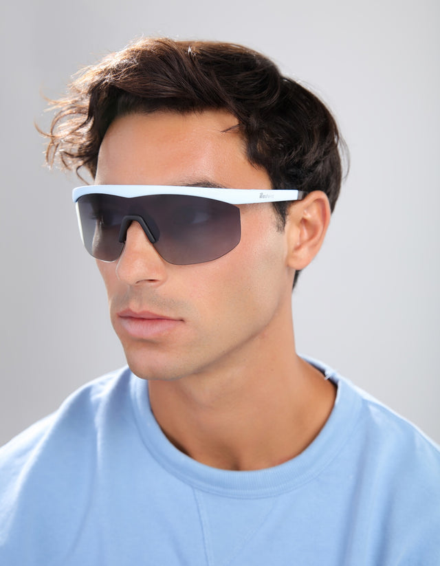 Man wearing a pair of Managua sunglasses with a white frame against a gray background