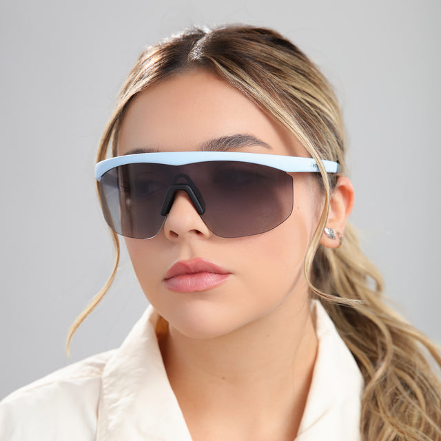 Blonde woman in a white linen blouse wearing Managua Sunglasses Matte Baby Blue with Grey Gradient