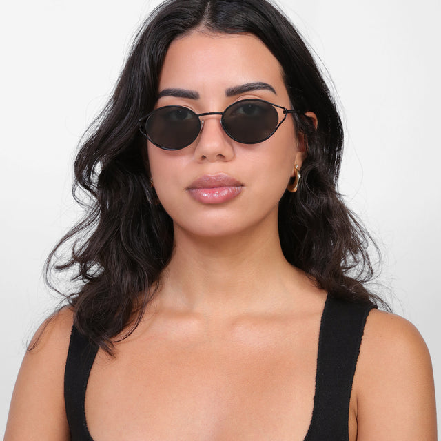 Brunette model with loose curls wearing Maria Sunglasses Black with Grey