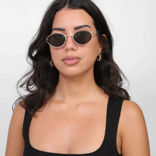 Brunette model with loose curls wearing Maria Sunglasses Gold with Grey