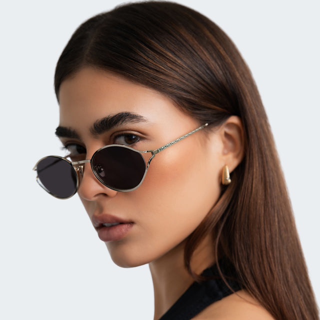 Another angle of woman in a black halter blouse wearing Maria Sunglasses Gold with Grey