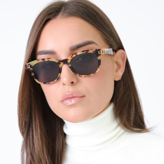 Brunette model in a white turtleneck wearing Melrose Sunglasses Tortoise with Grey Flat