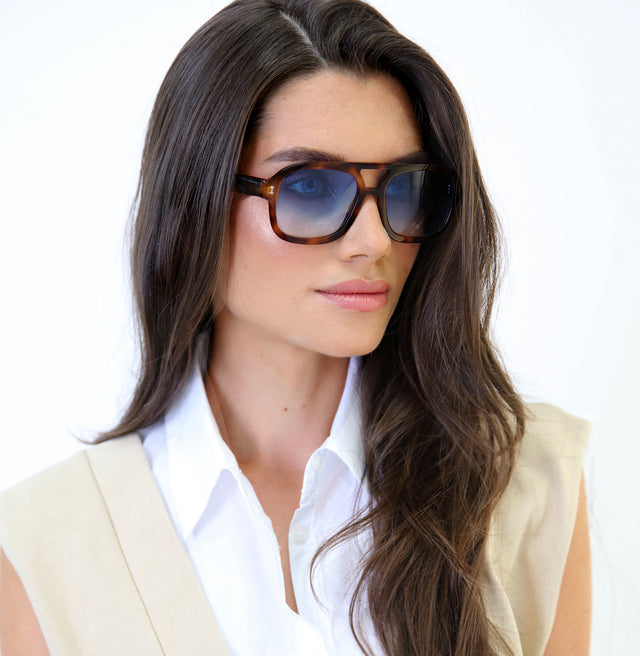 Angled pose of brunette model with wavy hair wearing Memphis Sunglasses Havana with Blue Gradient See Through