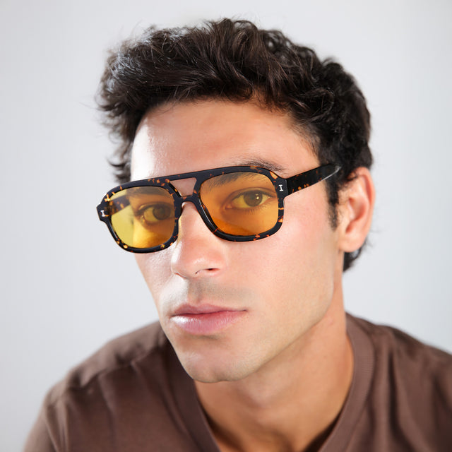 Man in a brown shirt wearing Memphis Sunglasses Flame with Honey See Through