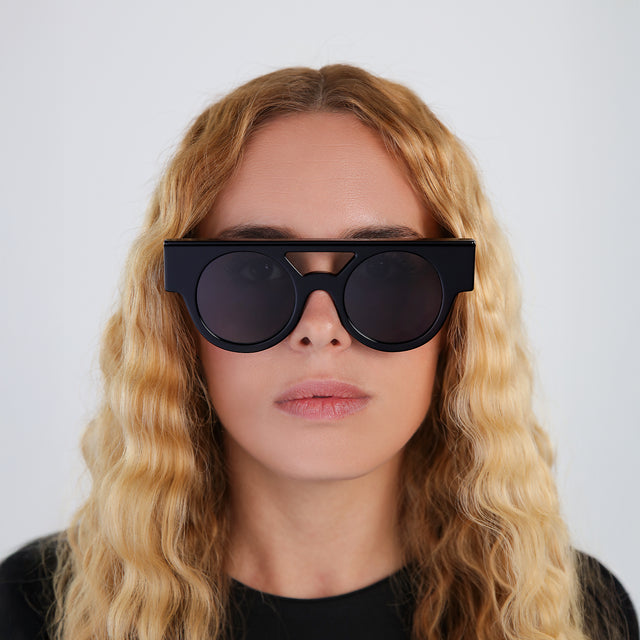 Another angle of a blond woman with wavy hair wearing Meyer (15 Year Anniversary) Sunglasses Black with Grey Flat