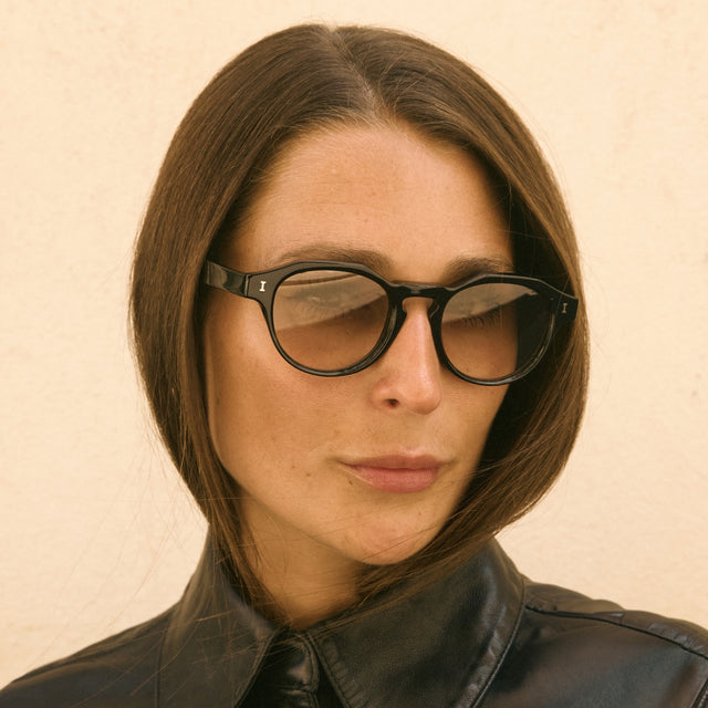 Woman in a black leather blouse wearing Michael Sunglasses Black with Taupe Gradient