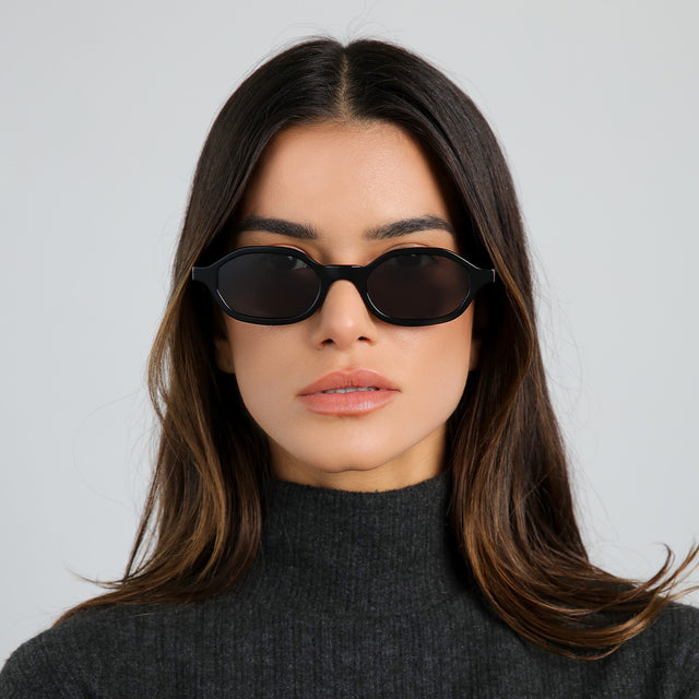 Brunette model in a heather grey cashmere turtleneck wearing Munich Sunglasses Black with Grey Flat