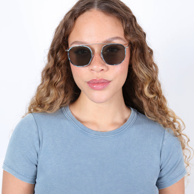 Brunette model with ombré, curled hair wearing Mykonos Ace Sunglasses Dark Ice/Silver with Olive Flat