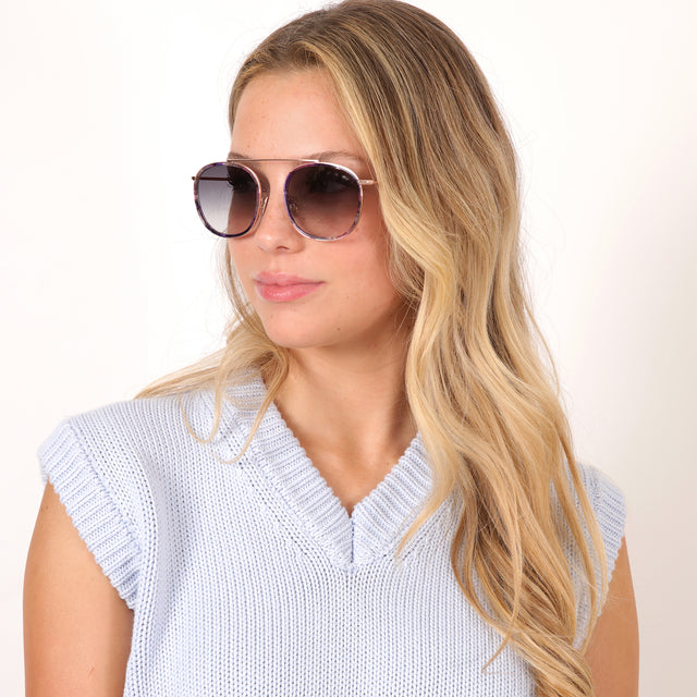 Blonde model with wavy hair wearing Mykonos Ace Sunglasses Iris/Rose Gold with Grey Flat Gradient