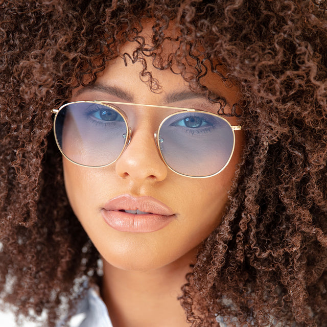 Brunette model with natural curly hair wearing Mykonos II Sunglasses Gold with Blue Flat Gradient See Through