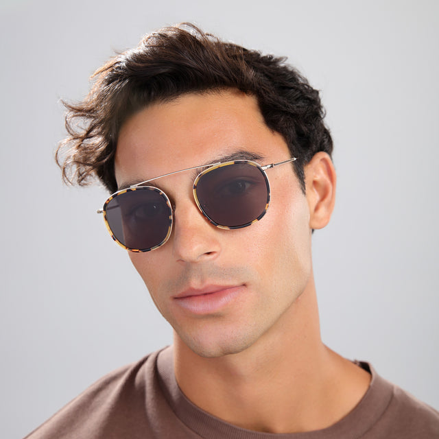 Man in a brown shirt wearing Mykonos Ace Sunglasses Tortoise/Gold with Grey Flat