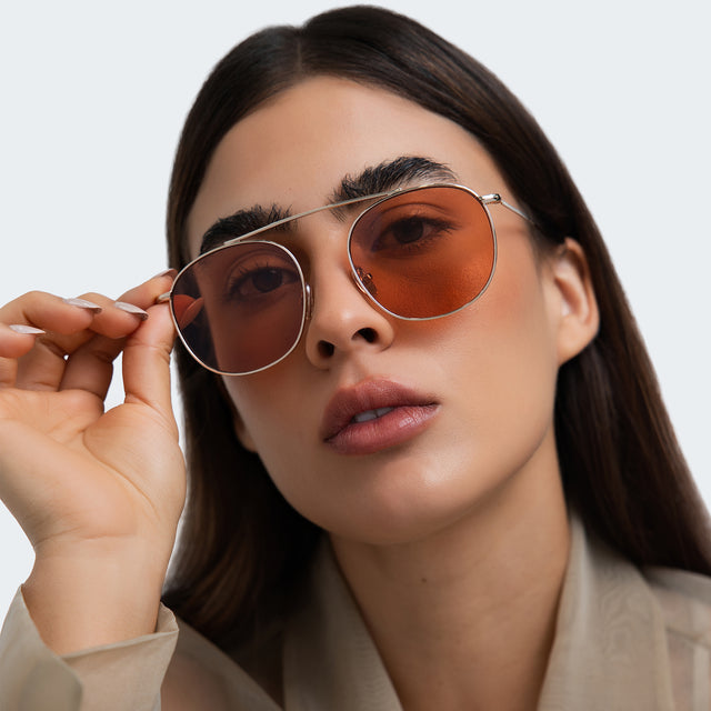 Woman in a taupe blouse wearing Mykonos M Sunglasses Gold with Sunset Flat
