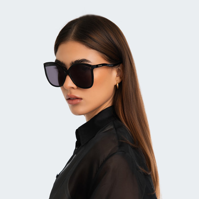 Woman in a black sheer blouse wearing Nancy 57 Sunglasses Black with Grey