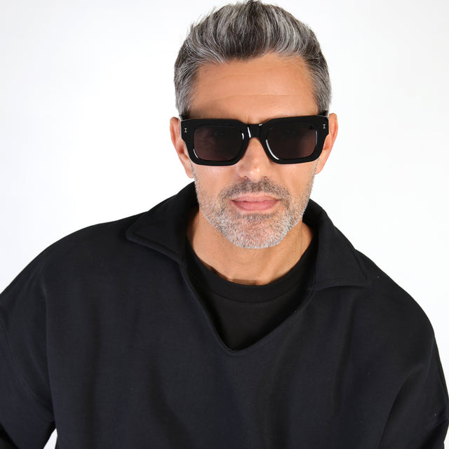 Model with salt and pepper hair and beard wearing Nick Kyrgios x illesteva 2 Sunglasses Black with Grey Flat
