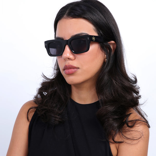Brunette model with loose curls wearing Nick Kyrgios x illesteva 2 Sunglasses Black with Grey Flat