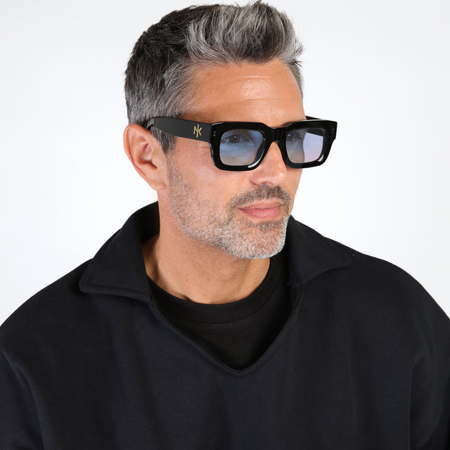 Model with salt and pepper hair and beard wearing Nick Kyrgios x illesteva 2 Sunglasses Black with Light Blue Flat See Through