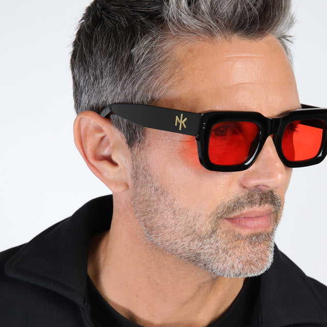 Close up of model with salt and pepper hair and beard wearing Nick Kyrgios x illesteva 2 Sunglasses Black with Red Flat See Through