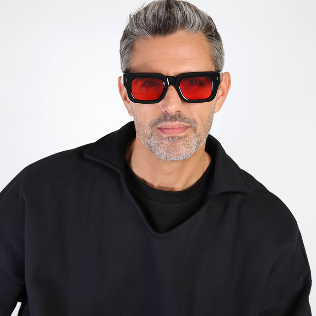 Model with salt and pepper hair and beard wearing Nick Kyrgios x illesteva 2 Sunglasses Black with Red Flat See Through