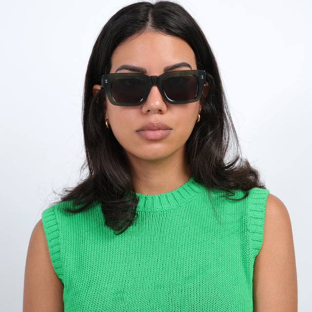 Brunette model in a bright green sweatervest wearing Nick Kyrgios x illesteva 2 Sunglasses Pine with Grey Flat