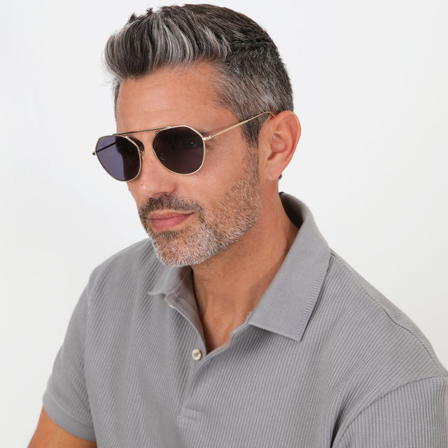 Model with salt and pepper hair and beard turned to his side wearing Nicosia 57 Sunglasses Gold with Grey Flat