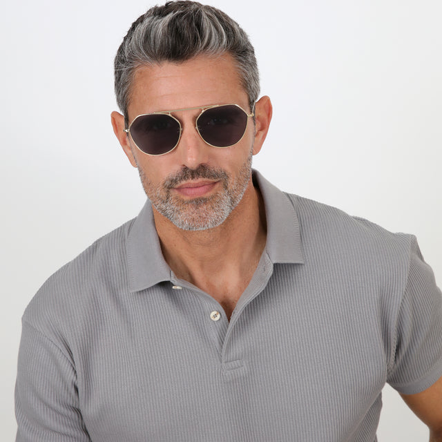 Model with salt and pepper hair and beard wearing Nicosia 57 Sunglasses Gold with Grey Flat