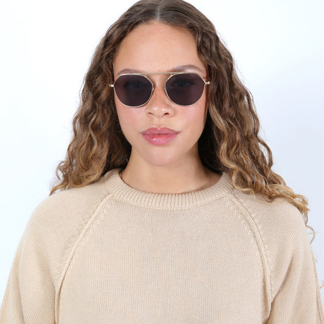 Brunette model with ombré natural curls wearing Nicosia 57 Sunglasses Gold with Grey Flat