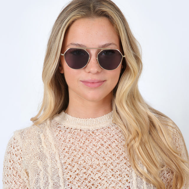 Blonde model with loose curls wearing Nicosia Sunglasses Gold with Grey Flat