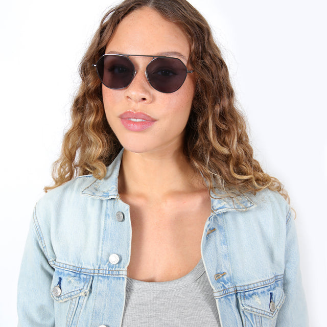 Brunette model with ombré, natural curls wearing Nicosia Sunglasses Gunmetal with Grey Flat