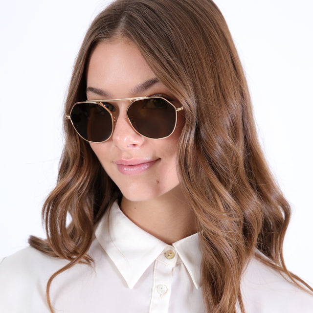 Brunette model with wavy hair wearing Nicosia Sunglasses Rose Gold with Brown Flat