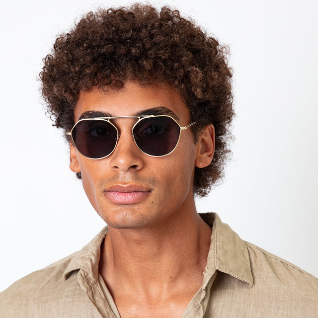 Model with afro-curly hair wearing Nicosia Sunglasses Rose Gold with Brown Flat