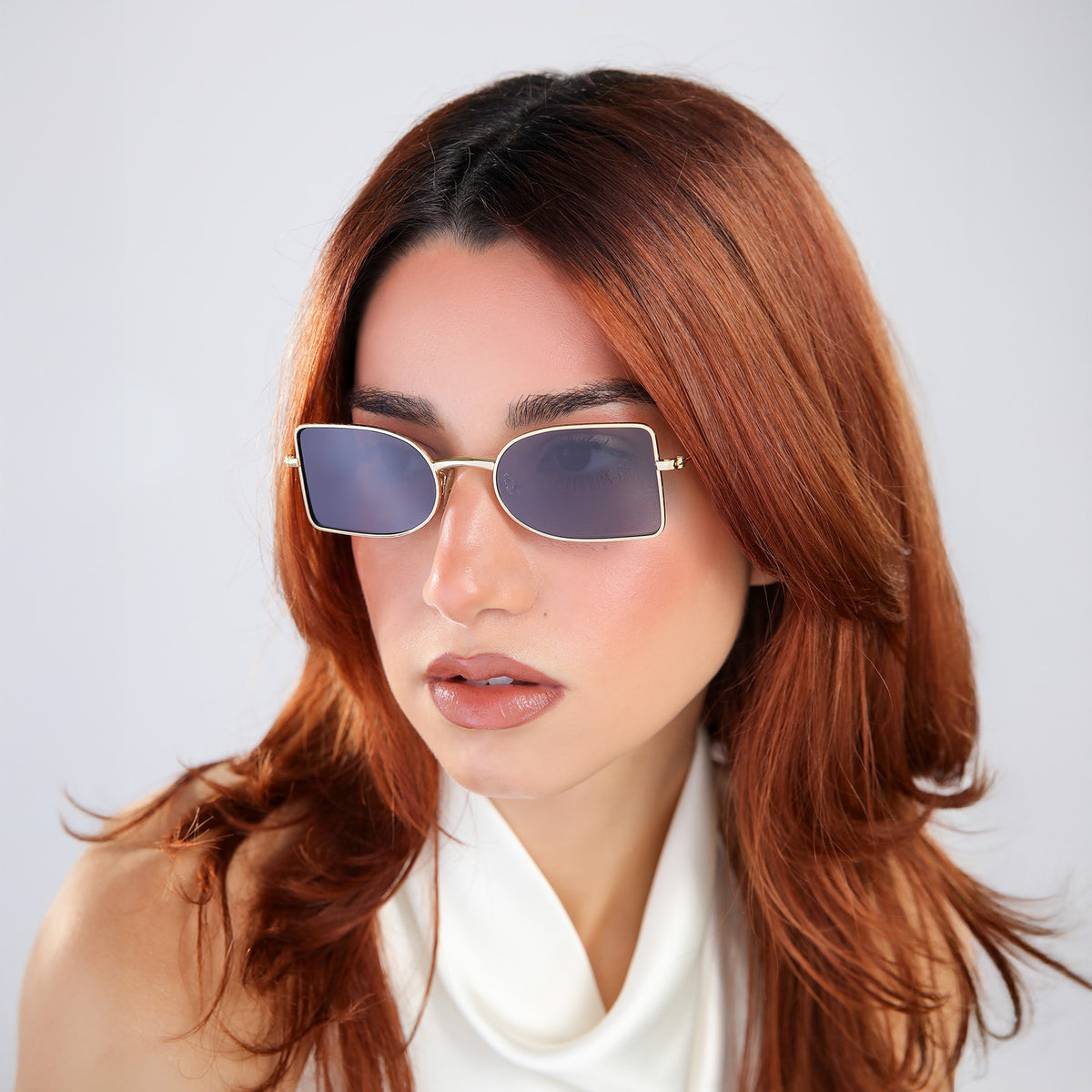 Woman wearing Nostrand Sunglasses in Gold with Grey lenses, side profile, Woman with red hair looking to her right