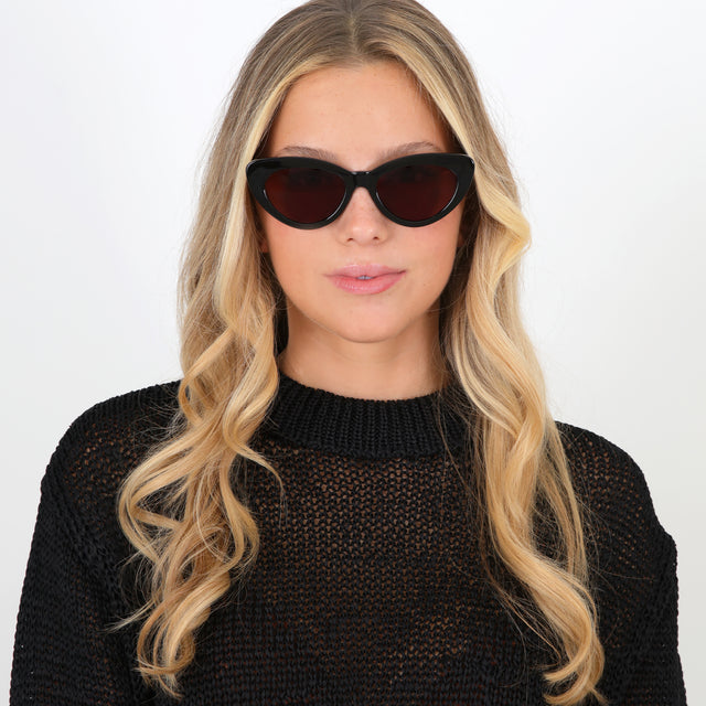 Blonde model with loose curls wearing Pamela Sunglasses Black with Brown Flat