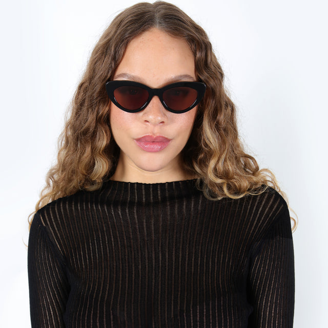 Brunette model with ombré curls wearing Pamela Sunglasses Black with Brown Flat