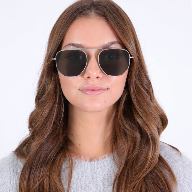 Brunette with loose curls wearing Patmos Sunglasses Silver with Olive Flat