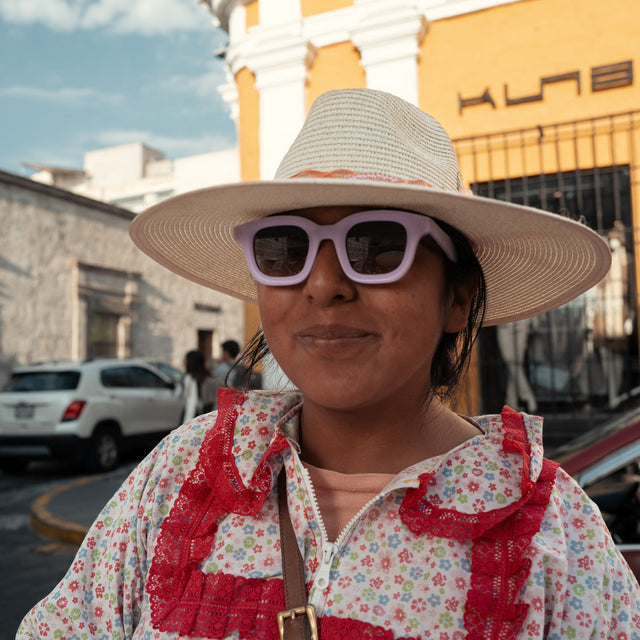 Young Peruvian woman in a brimmed hat wearing George Sunglasses in Matte Lilac