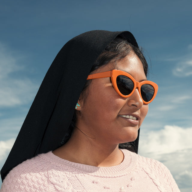 Young Peruvian woman looking into a deep blue sky wearing Pamela Sunglasses in Aperol