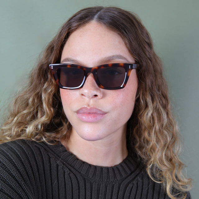 Brunette model with ombré natural curls wearing Portugal Sunglasses Havana with Grey Flat