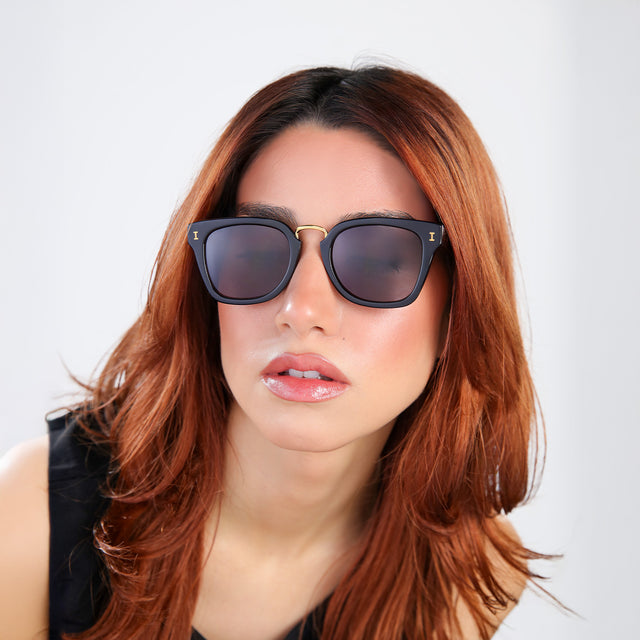 Another angle of woman with red hair in a black blouse wearing Positano Sunglasses Black/Gold with Grey