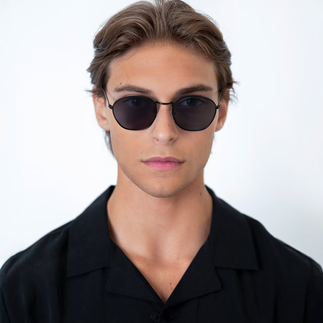 Model with short, light brown hair wearing Prince Sunglasses Black with Grey Flat