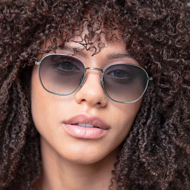 Brunette model with natural small curls wearing Prince Sunglasses Gunmetal with Grey Flat Gradient