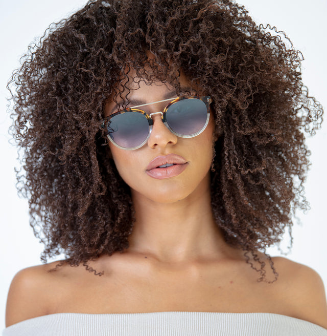Brunette model with afro-curly hair wearing Puglia Sunglasses H/H Maple Bone/Gold with Silver Flat Mirror Gradient