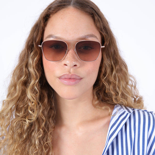 Brunette model with ombré, curly hair wearing Samos Sunglasses Rose Gold with Brown Flat Gradient