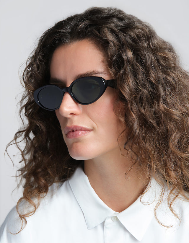 Woman wearing Sheila Sunglasses in black and a white shirt