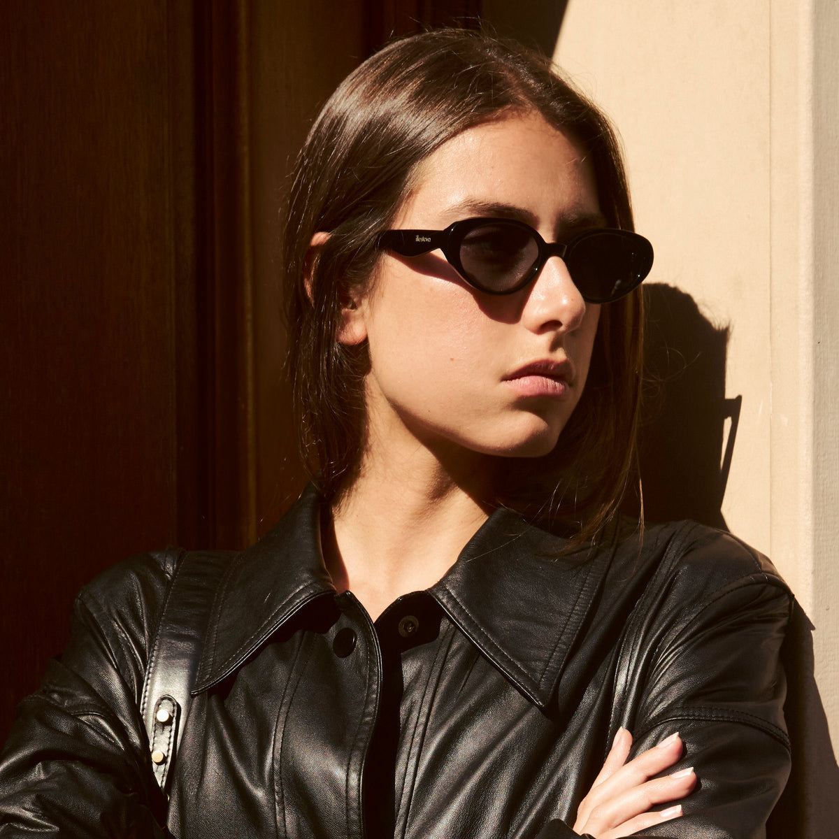 Woman wearing Sheila Sunglasses in Black with Grey Flat lenses, Woman in Paris wearing a black leather jacket